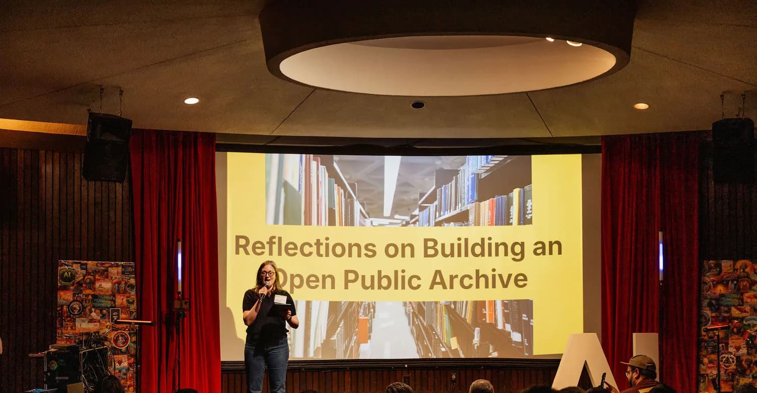 Andrea Mills speaking beside a projection of Internet Archive collection pages.
