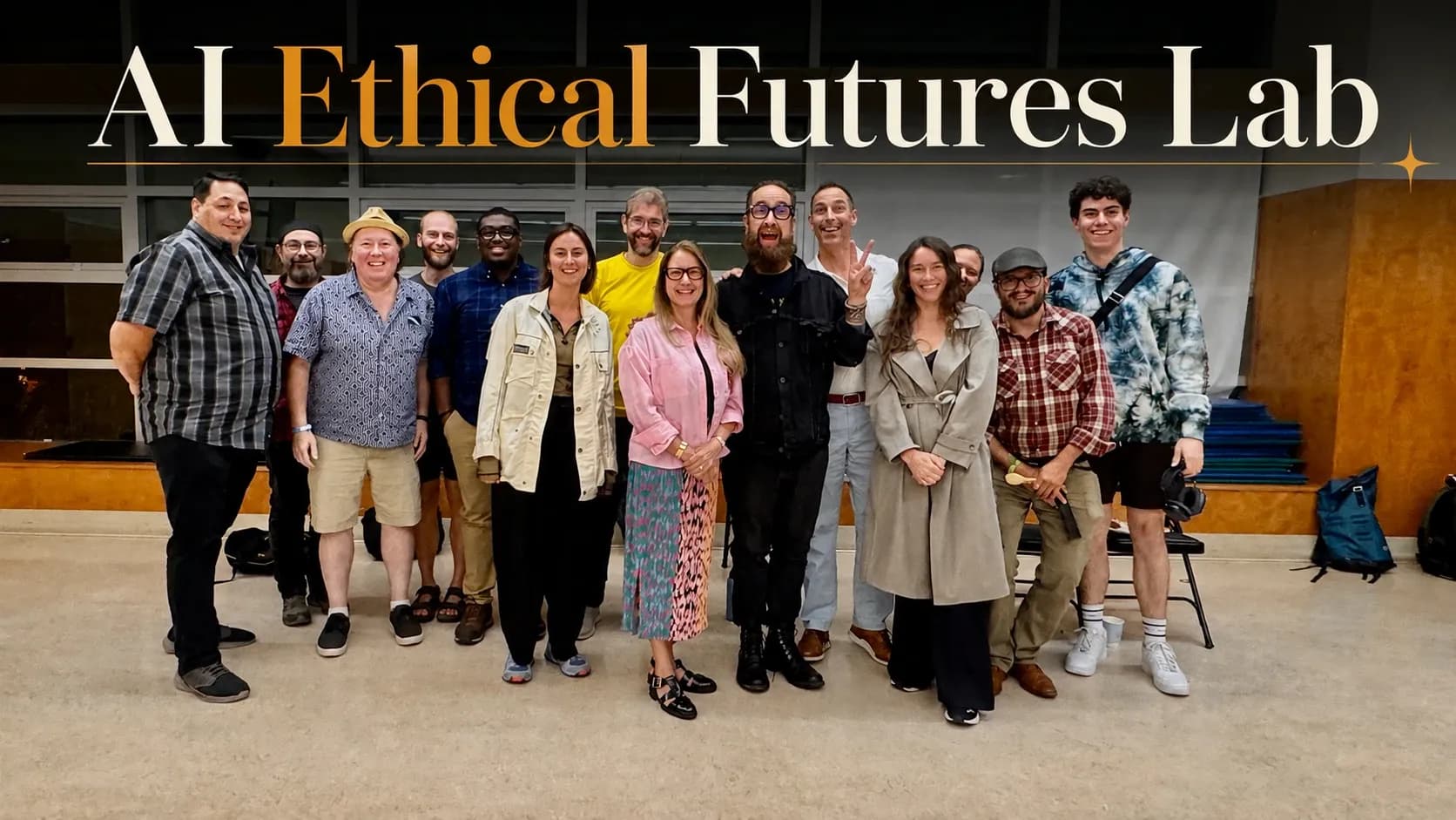Fourteen members of the AI Ethical Futures Lab standing together in a row at Mount Pleasant Community Centre after Lab number 7, smiling, with the words AI Ethical Futures Lab set above them.