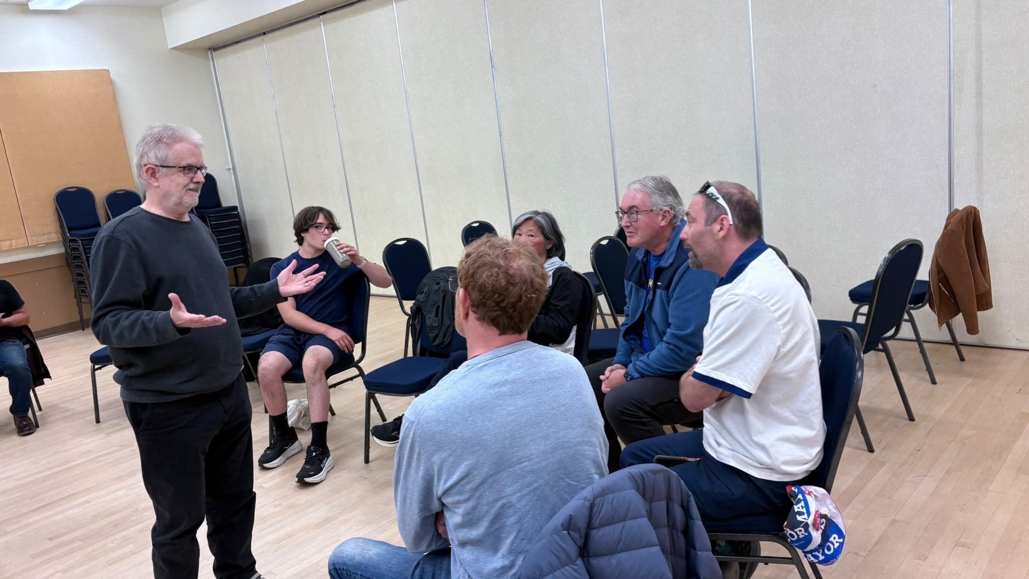 A participant gestures while others listen in a smaller conversation.