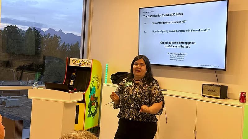 Dr. Alma Barranco-Mendoza speaks beside a screen reading "The Question for the Next 30 Years: not how intelligent can we make AI, but how intelligently can AI participate in the real world."