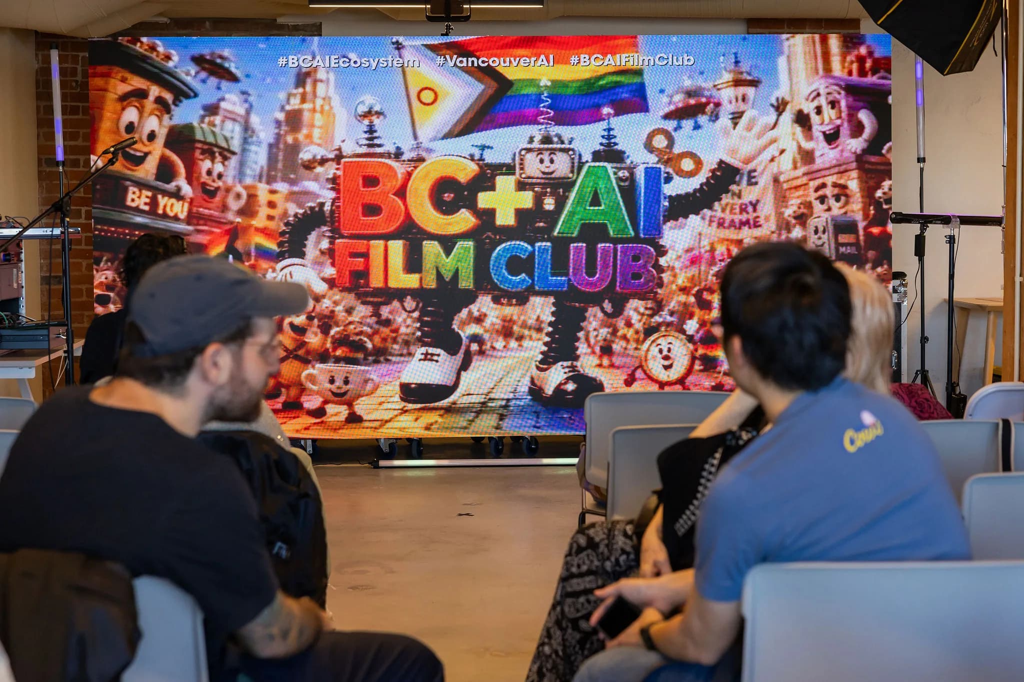 Audience members settling in beneath the BC + AI Film Club screen at the June meetup.