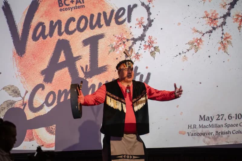 An Indigenous welcome performer holds a hand drum wide on the Vancouver AI Community stage.