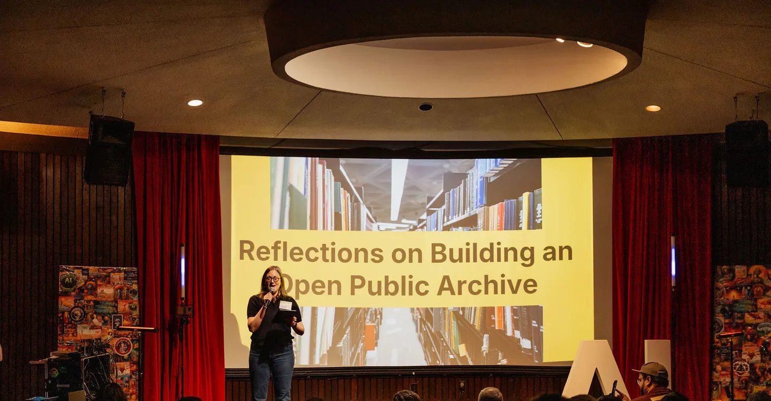 Andrea Mills speaking beside a projection of Internet Archive collection pages.