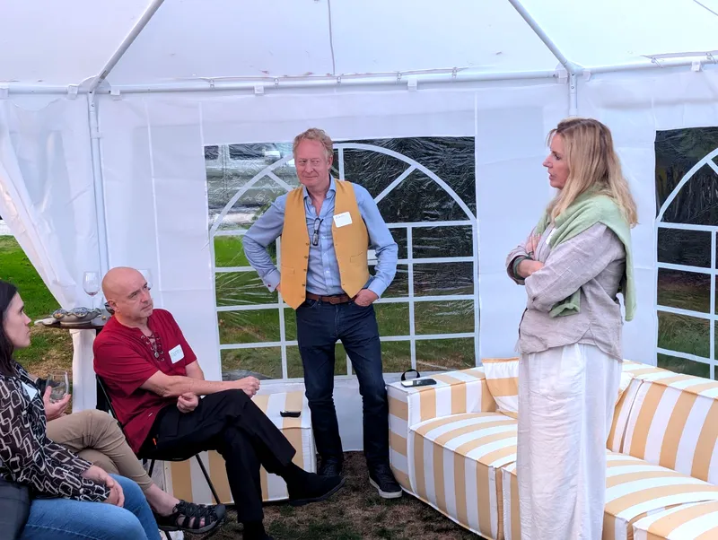 Four people talking around the striped couches under the tent after the formal talks.