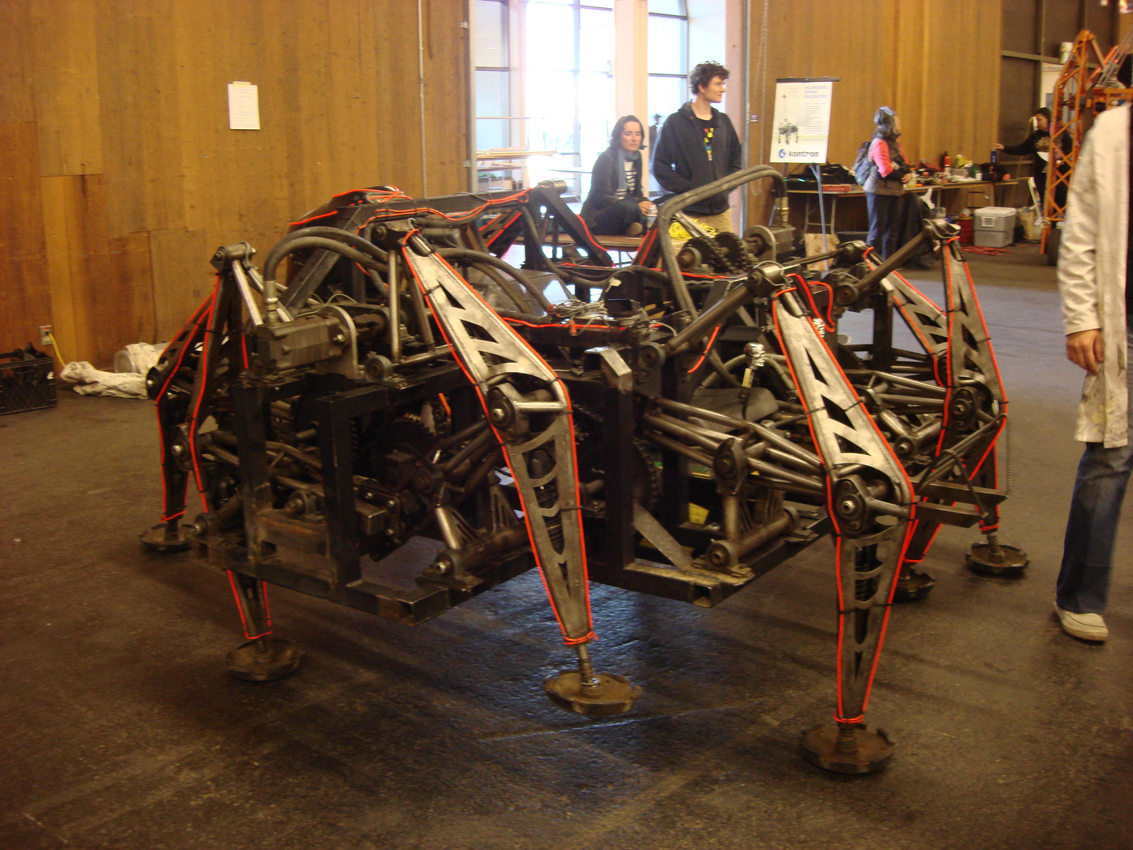 Mondo Spider displayed indoors, showing its exposed frame, eight articulated legs and mechanical linkages.