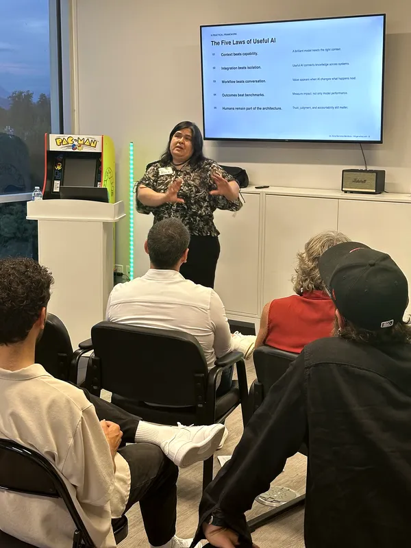 Dr. Alma Barranco-Mendoza presents her closing slide, "The Five Laws of Useful AI," beside a Pac-Man cabinet in the meetup room.