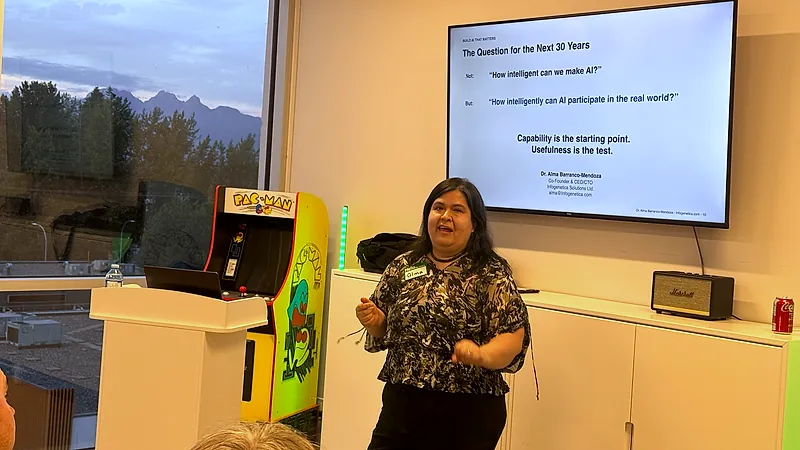 Dr. Alma Barranco-Mendoza speaks beside a screen reading "The Question for the Next 30 Years: not how intelligent can we make AI, but how intelligently can AI participate in the real world."