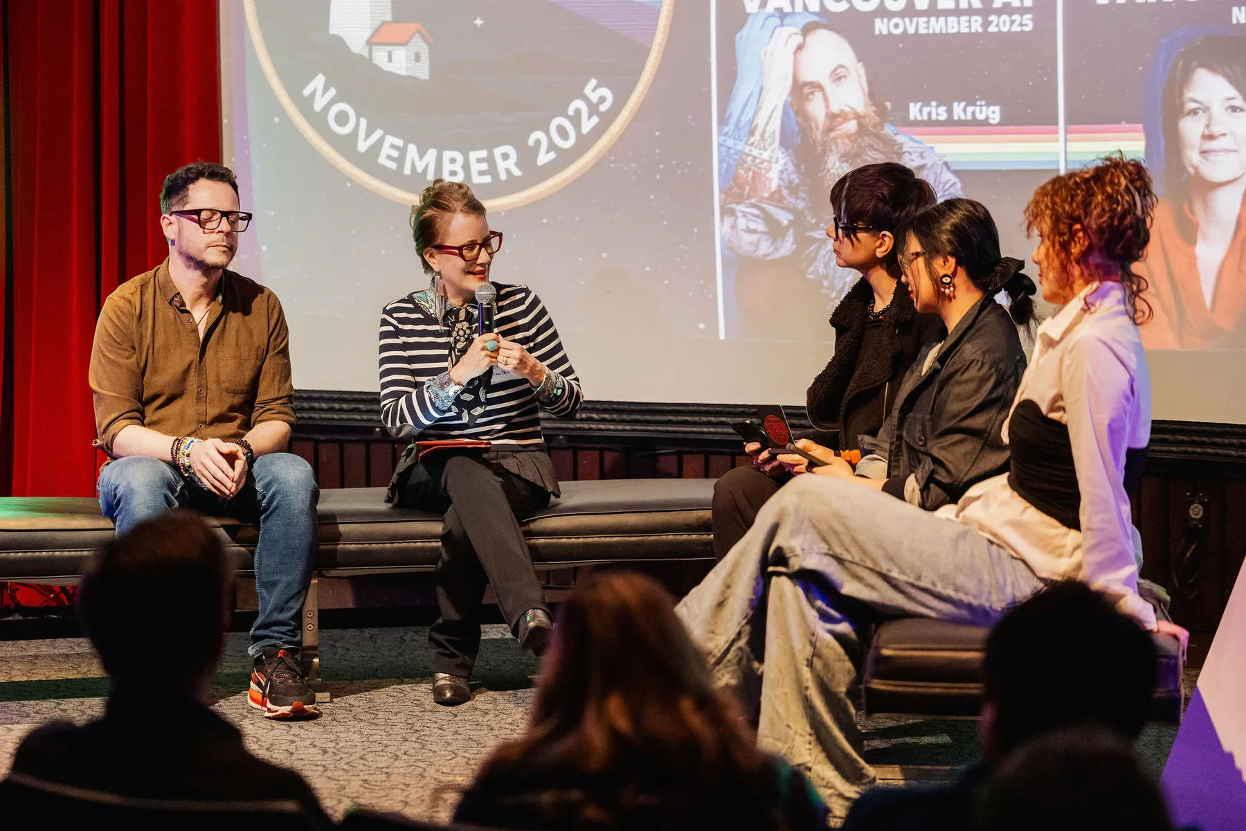 Five panelists seated on a low stage at a Vancouver AI Community meetup, one speaking into a microphone, the November 2025 speaker lineup projected behind them.