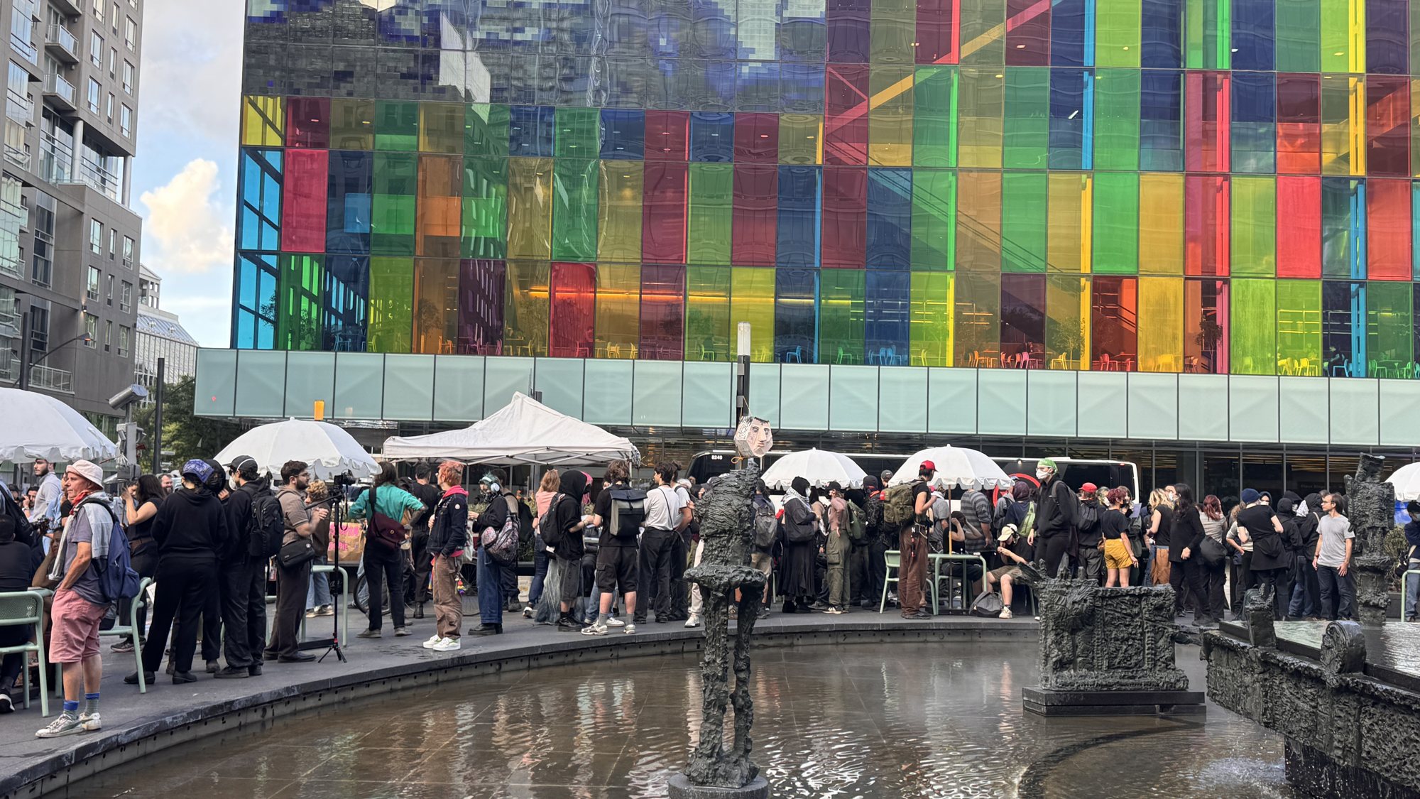 Demonstrators gathered beside the fountain across from the multicoloured glass facade of the Palais des congrès.