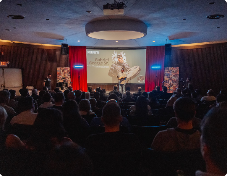 Gabriel George Sr. speaks on stage to a seated Vancouver AI audience.