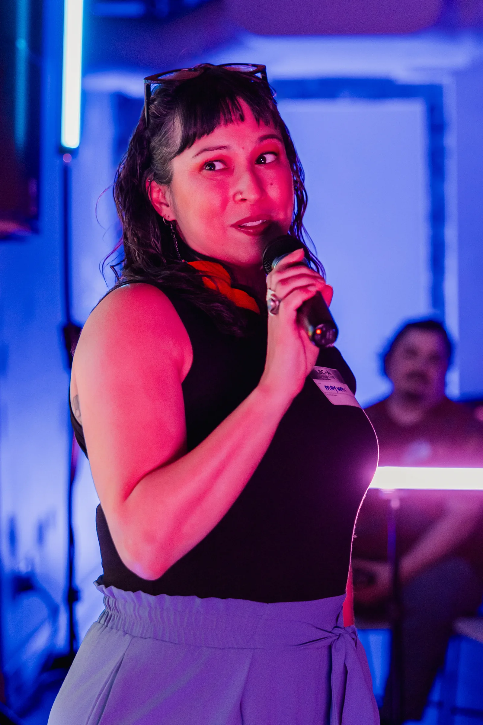 AI Film Club speaker with microphone under blue and magenta event lighting.