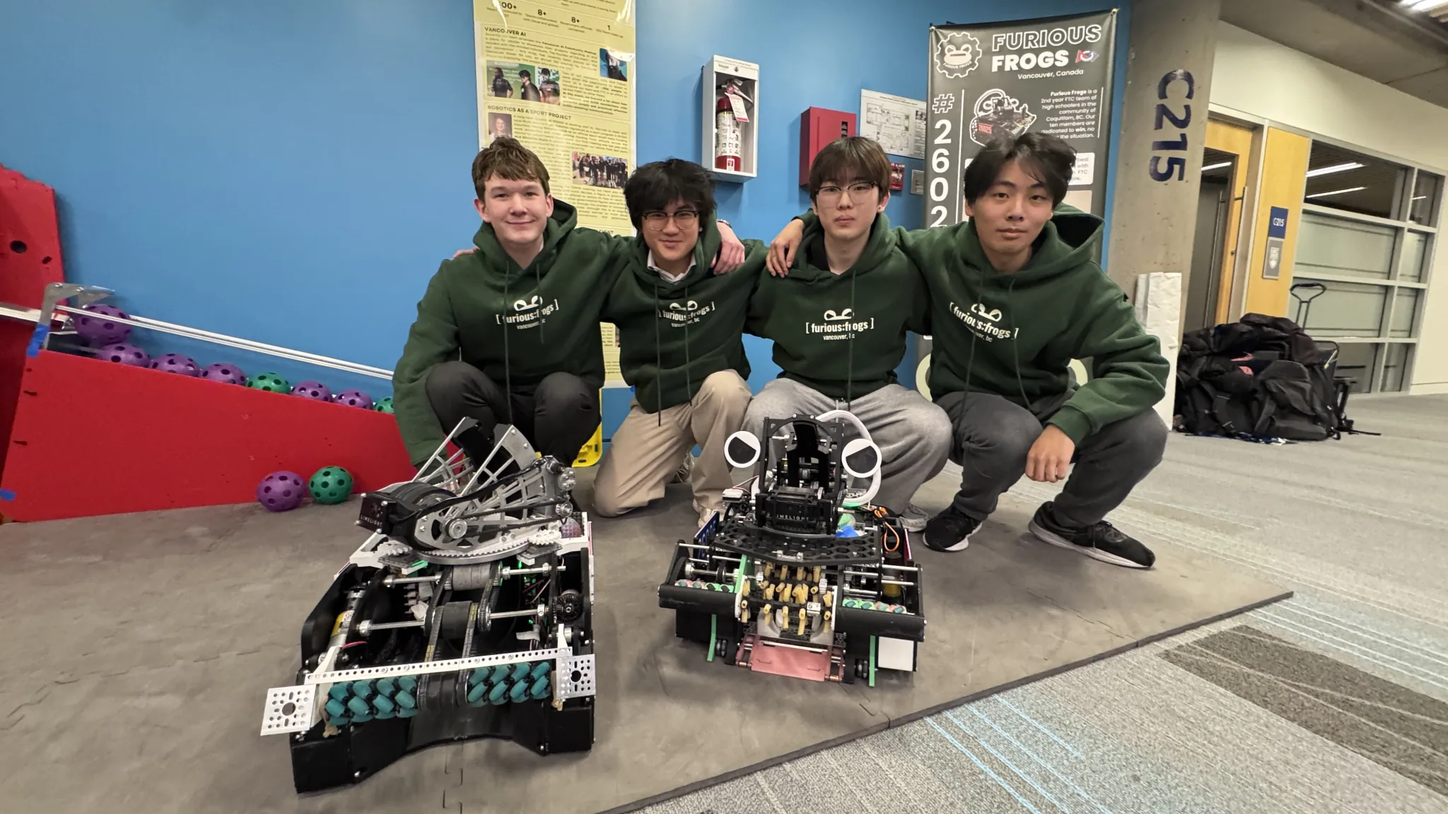 Furious Frogs students pose with two competition robots and a team banner at the FIRST Tech Challenge World Championship.
